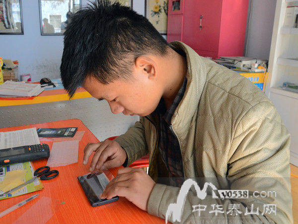 刘彬在专注地为顾客贴手机膜。通讯员 王耀峰 摄